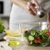 woman salting a bowl of vegetables