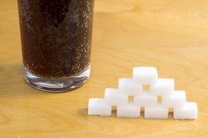 glass of soda next to sugar cubes